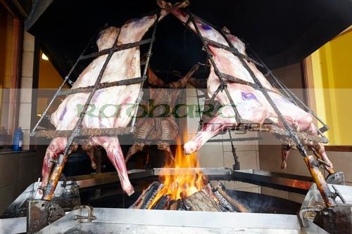 argentine asado whole lamb roasting over burning open fire in restaurant window Ushuaia Argentina