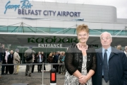 Barbara-McNarry-Dickie-Best-in-front-Belfast-City-Airports-new-logo-at-George-Best-airport-renaming-ceremony,-Belfast-City-Airport,-Belfast,-Northern-Ireland.