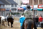 man-in-cowboy-hat-riding-horse-down-main-street-during-ballyclare-may-fair-county-antrim-northern-ireland