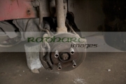 older-car-up-on-bricks-with-wheel-removed-showing-brake-discs-suspension