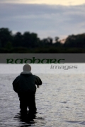 fisherman-fly-fishing-on-Stoneyford-Reservoir-at-sunset,-county-antrim-northern-ireland