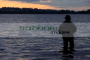 fisherman-fly-fishing-on-Stoneyford-Reservoir-at-sunset,-county-antrim-northern-ireland