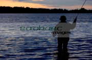 fisherman-fly-fishing-on-Stoneyford-Reservoir-at-sunset,-county-antrim-northern-ireland