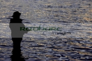fisherman-fly-fishing-on-Stoneyford-Reservoir-at-sunset,-county-antrim-northern-ireland