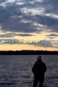 fisherman-fly-fishing-on-Stoneyford-Reservoir-at-sunset,-county-antrim-northern-ireland