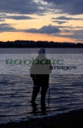 fisherman-fly-fishing-on-Stoneyford-Reservoir-at-sunset,-county-antrim-northern-ireland