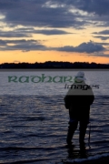 fisherman-fly-fishing-on-Stoneyford-Reservoir-at-sunset,-county-antrim-northern-ireland
