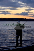 fisherman-fly-fishing-casting-on-Stoneyford-Reservoir-at-sunset,-county-antrim-northern-ireland