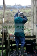 Man-in-hunting-clothes-ear-defenders-takes-aim-with-shotgun-in-shooting-stand-on-december-shooting-day,-county-antrim,-Northern-Ireland
