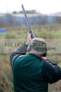 Man-in-hunting-clothes-ear-defenders-takes-aim-with-shotgun-in-shooting-stand-on-december-shooting-day,-county-antrim,-Northern-Ireland