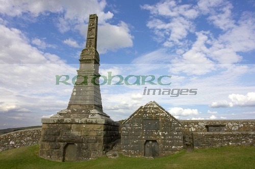 remains-high-stone-celtic-cross-on-OScally-monument-with-mausoleum-against-blue-cloudy-sky-in-the-Rock-Cashel,-Cashel,-County-Tipperary,-Republic-Ireland