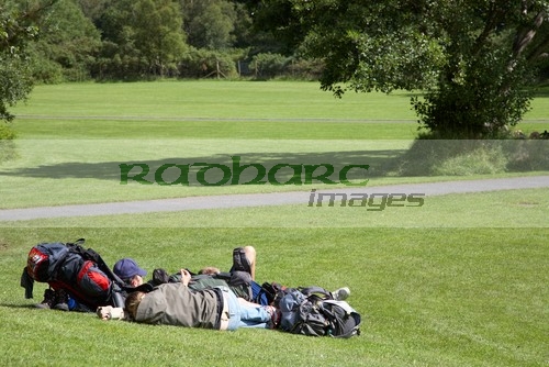 tourists-lying-on-the-grass-soaking-up-the-sun-with-backpacks-open-ground-in-grounds-glenalough-monastic-site