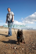 early-30s-man-out-walking-small-terrier-dog-on-beach-in-the-uk