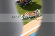 secretly-looking-out-through-balcony-down-onto-unsuspecting-sunbathing-woman-in-the-grounds-hotel