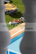 vertical-secretly-looking-out-through-balcony-down-onto-unsuspecting-sunbathing-woman-by-the-poolside-in-the-grounds-hotel