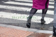business-woman-walking-over-textured-pedestrian-crossing-pavement-in-the-wet-in-the-uk